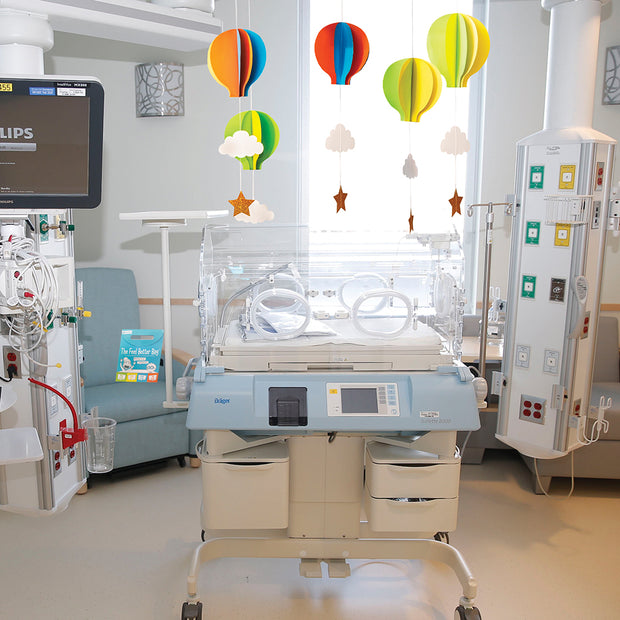 Open the Joy Hot air ballon room decor kit hanging over a premature baby bassinet in a hospital room in the nicu 